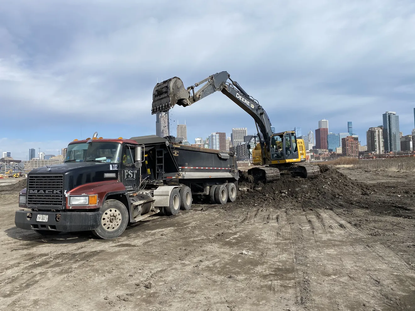 A wheel loader loading excavated soil into a haul truck for off-site disposal after classification