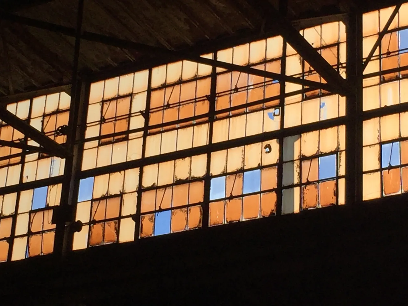Light through the window wall of an aging industrial building — the kind of 'facility' a purchaser shields themselves on with a Baseline Environmental Assessment